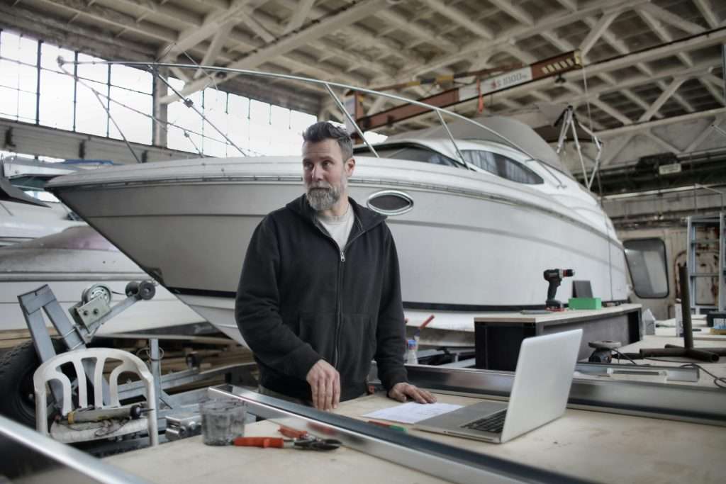 Marine mechanic working around a boat with a laptop